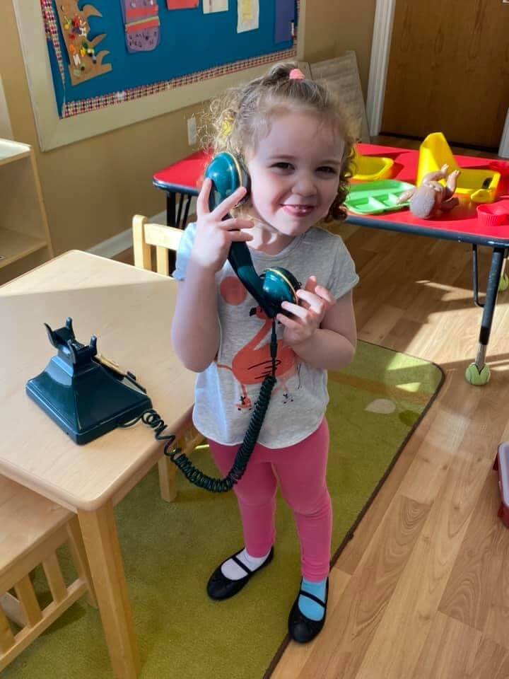 Preschool student holding a fake telephone to her ear